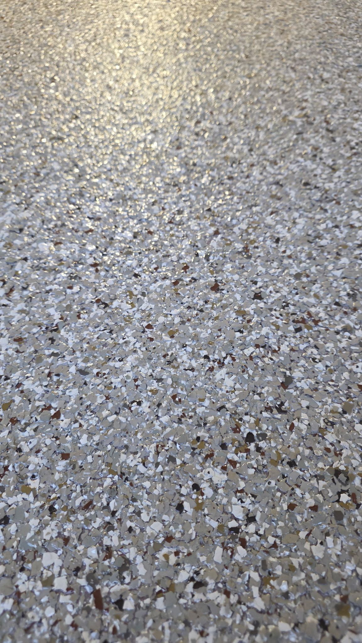 Speckled gray terrazzo floor with bright light reflecting from the upper left.