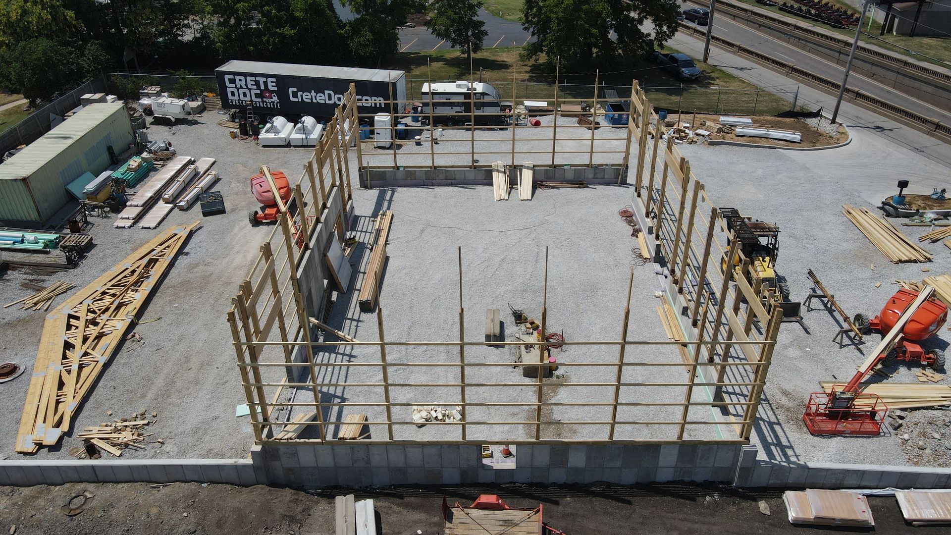 Construction site with concrete foundation, steel rebar framing, and two orange excavators.