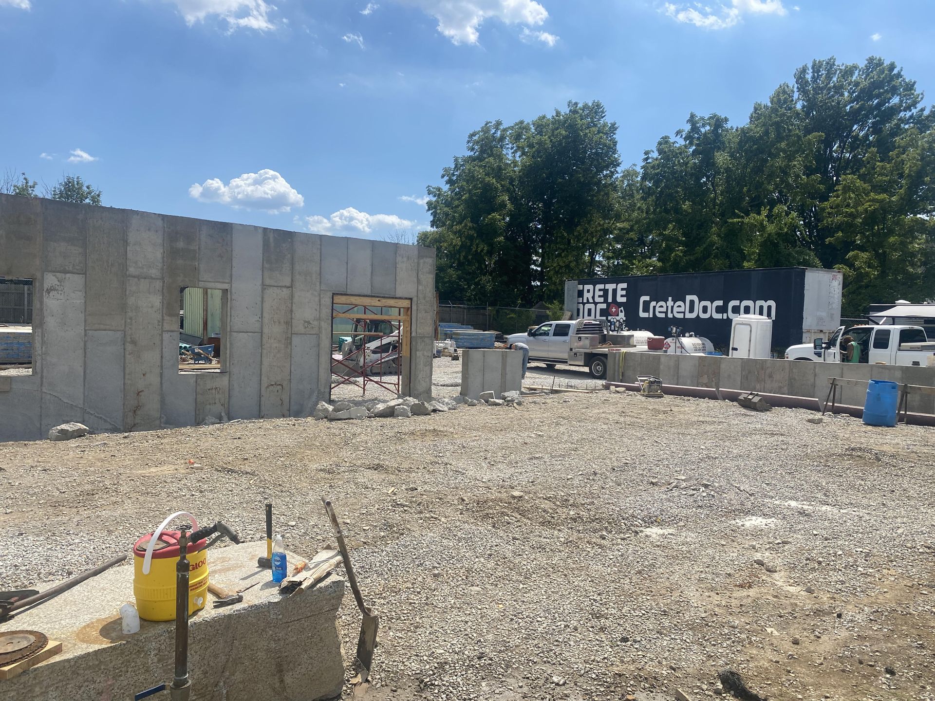 Construction site with concrete walls, gravel ground, and a CoreyDoc.com banner under a blue sky.