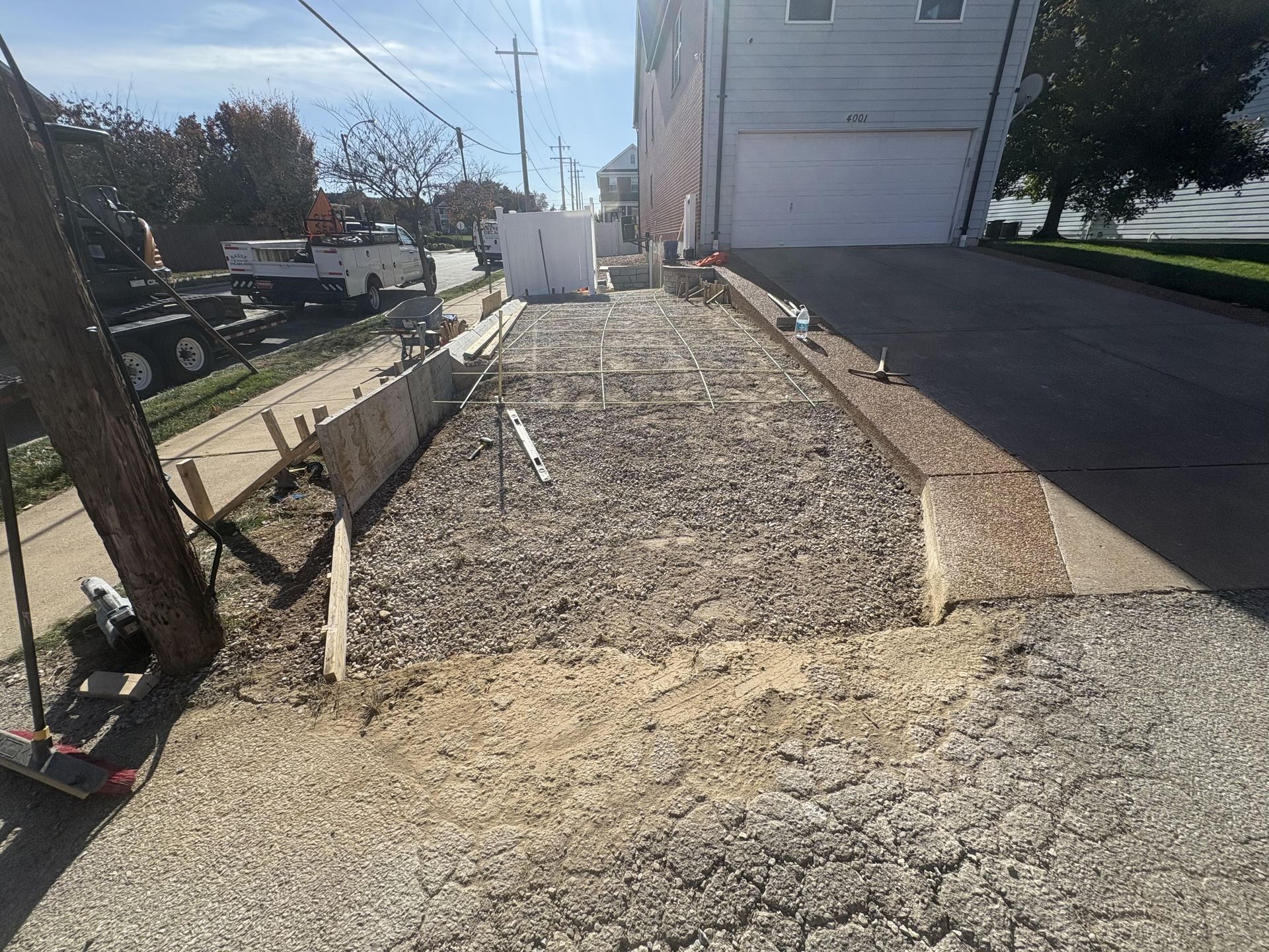 Gravel driveway under construction beside a house, with wooden edging and a walkway along the side.