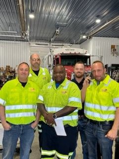 A group of men are posing for a picture in front of a truck.