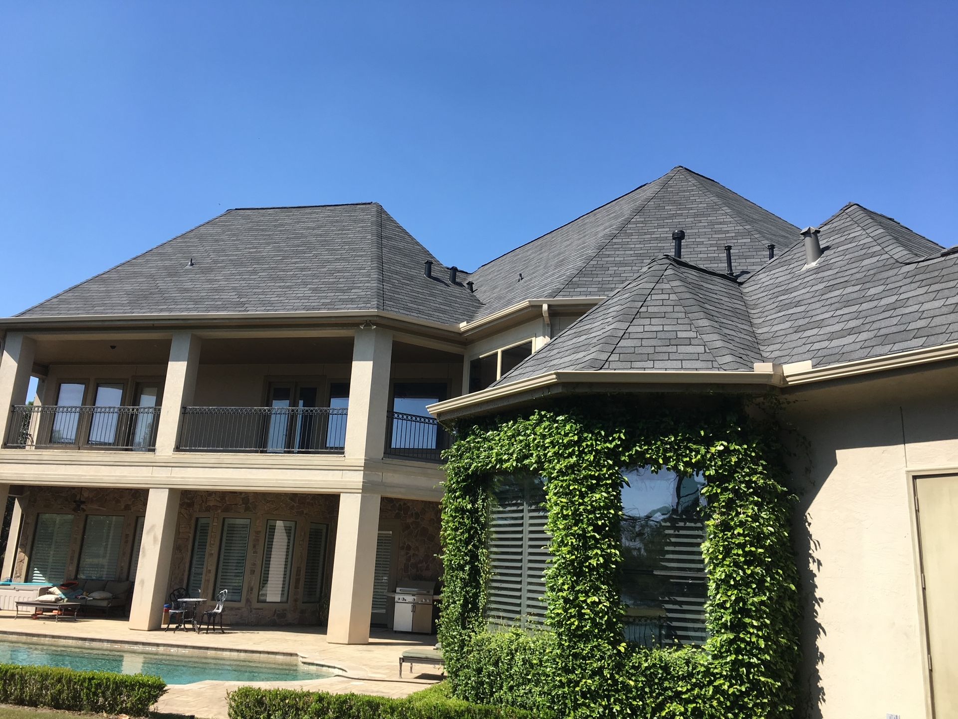Suburban house with a manicured lawn, trees, and a driveway under a blue sky
