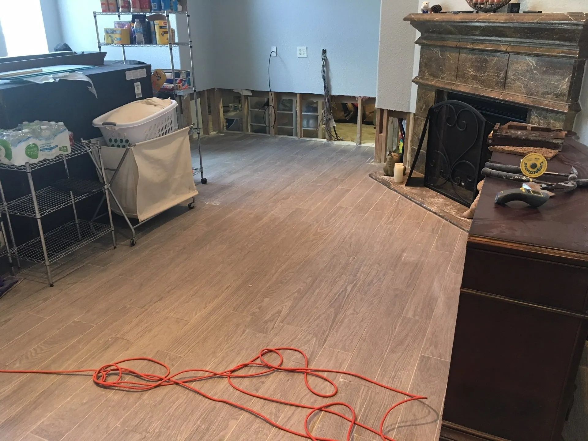 Living room with wood floor, fireplace, furniture, and an orange cord stretched across the floor