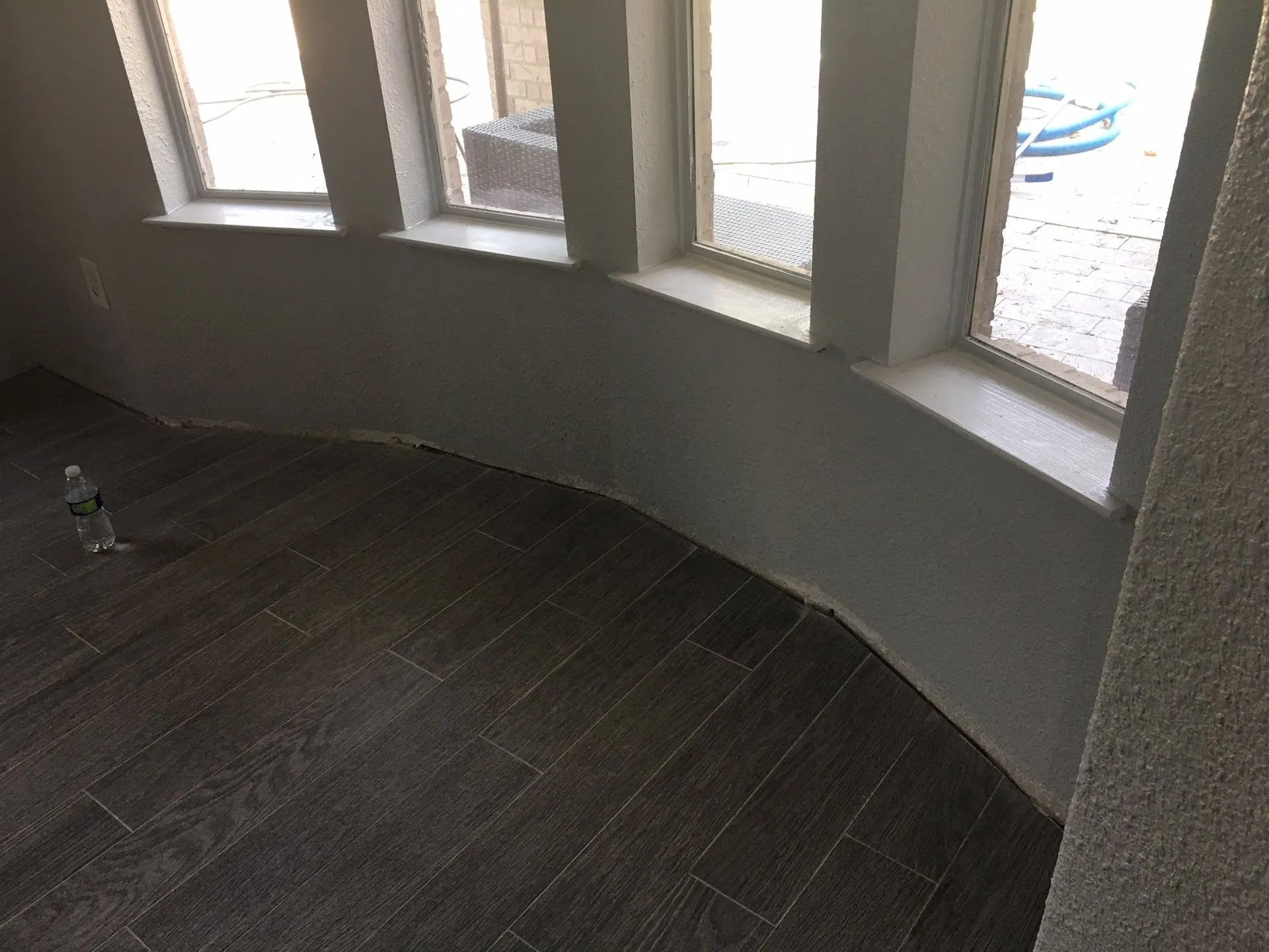 Curved interior wall with tall windows overlooking a patio and dark wood floor