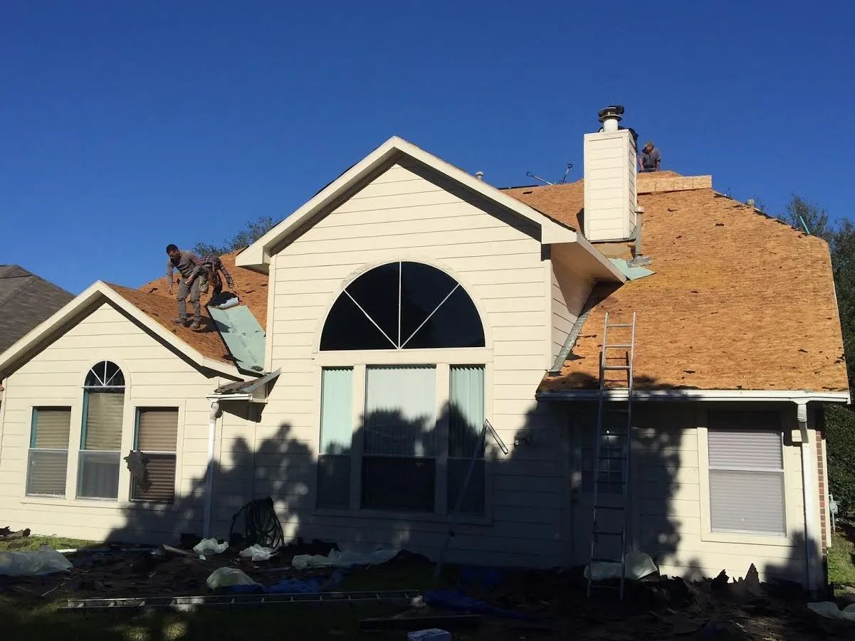 Suburban house with a large arched window and tan siding under a clear blue sky