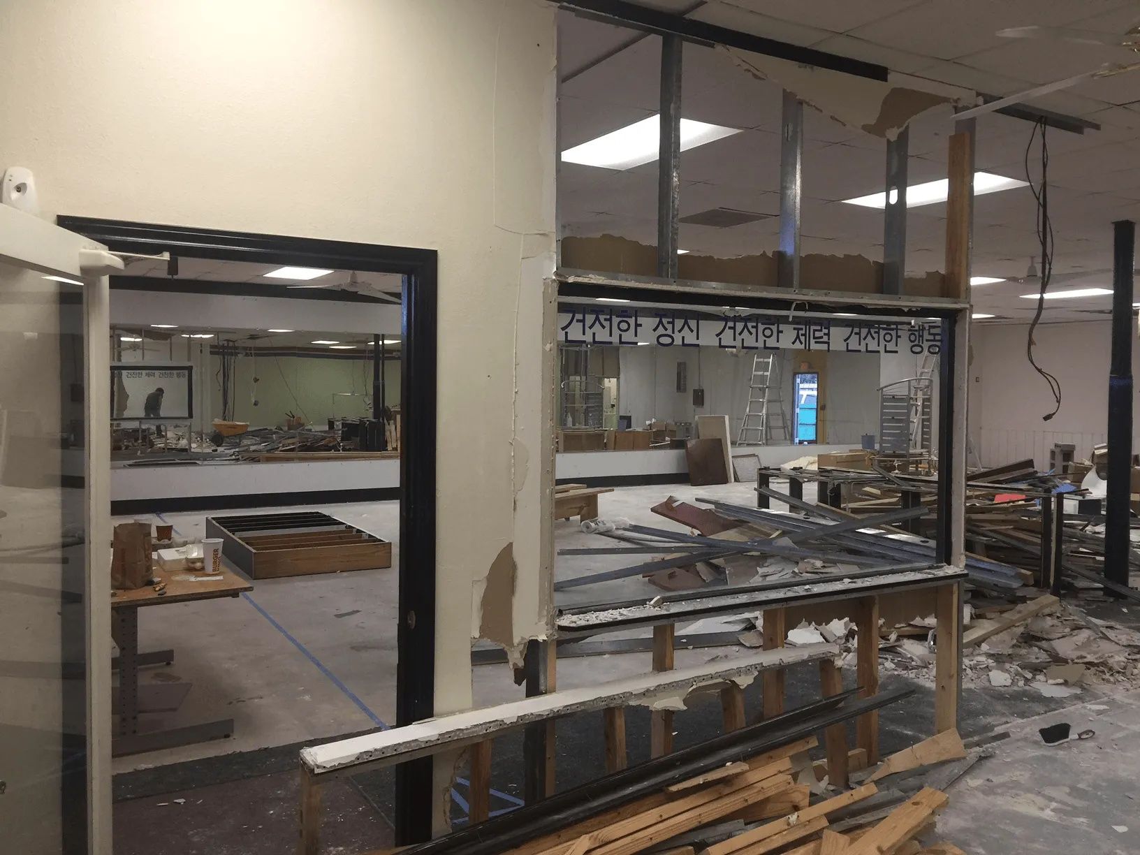 Damaged storefront interior with broken glass, debris, and exposed framing during renovations or storm damage