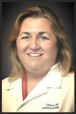 A woman in a white lab coat is smiling for the camera.