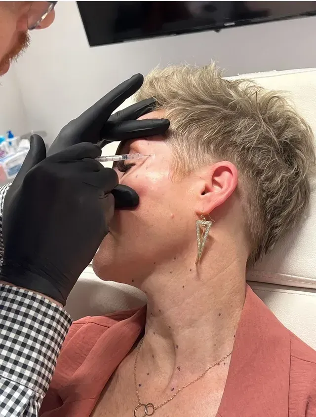 A woman is getting a botox injection in her face