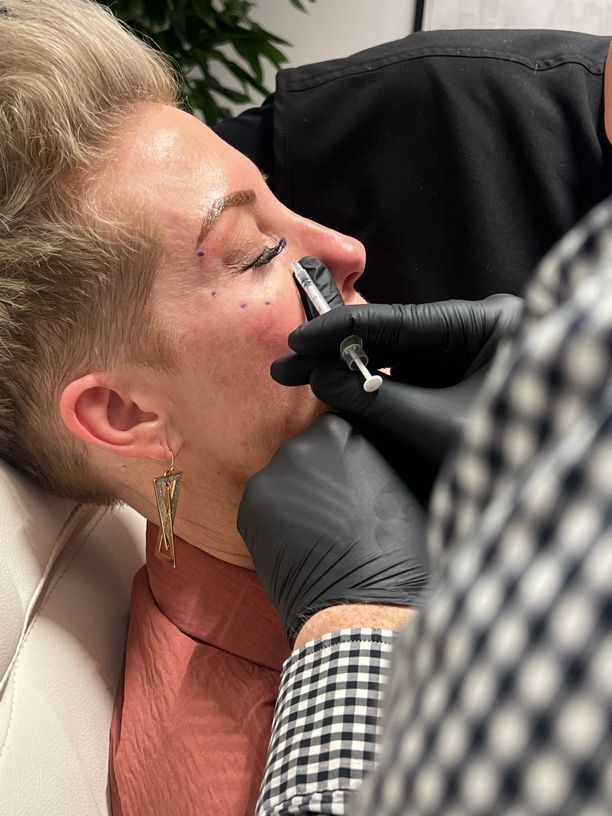 A woman is getting a botox injection in her face.
