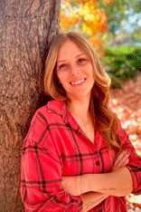 A woman is sitting on a bench in front of a playground.