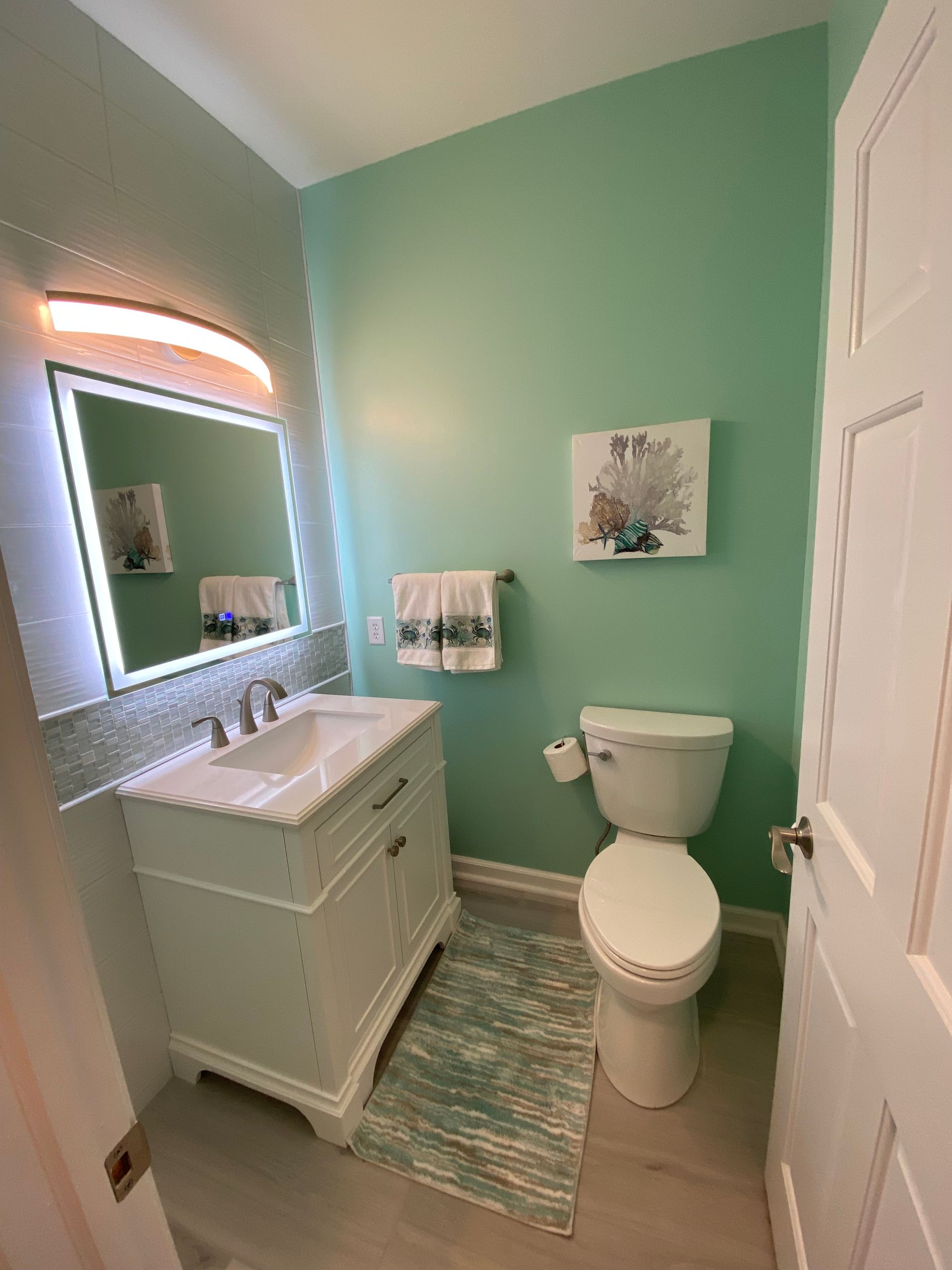 A bathroom with a toilet , sink and mirror.