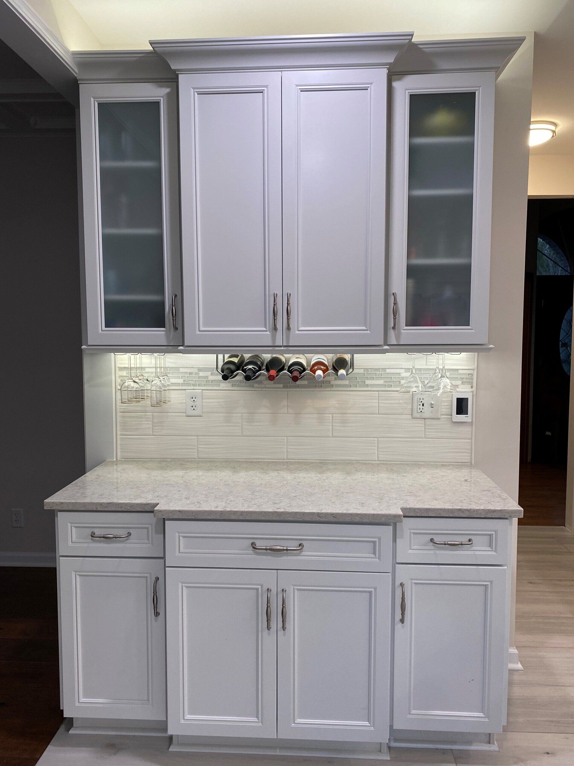 A kitchen with white cabinets and granite counter tops.