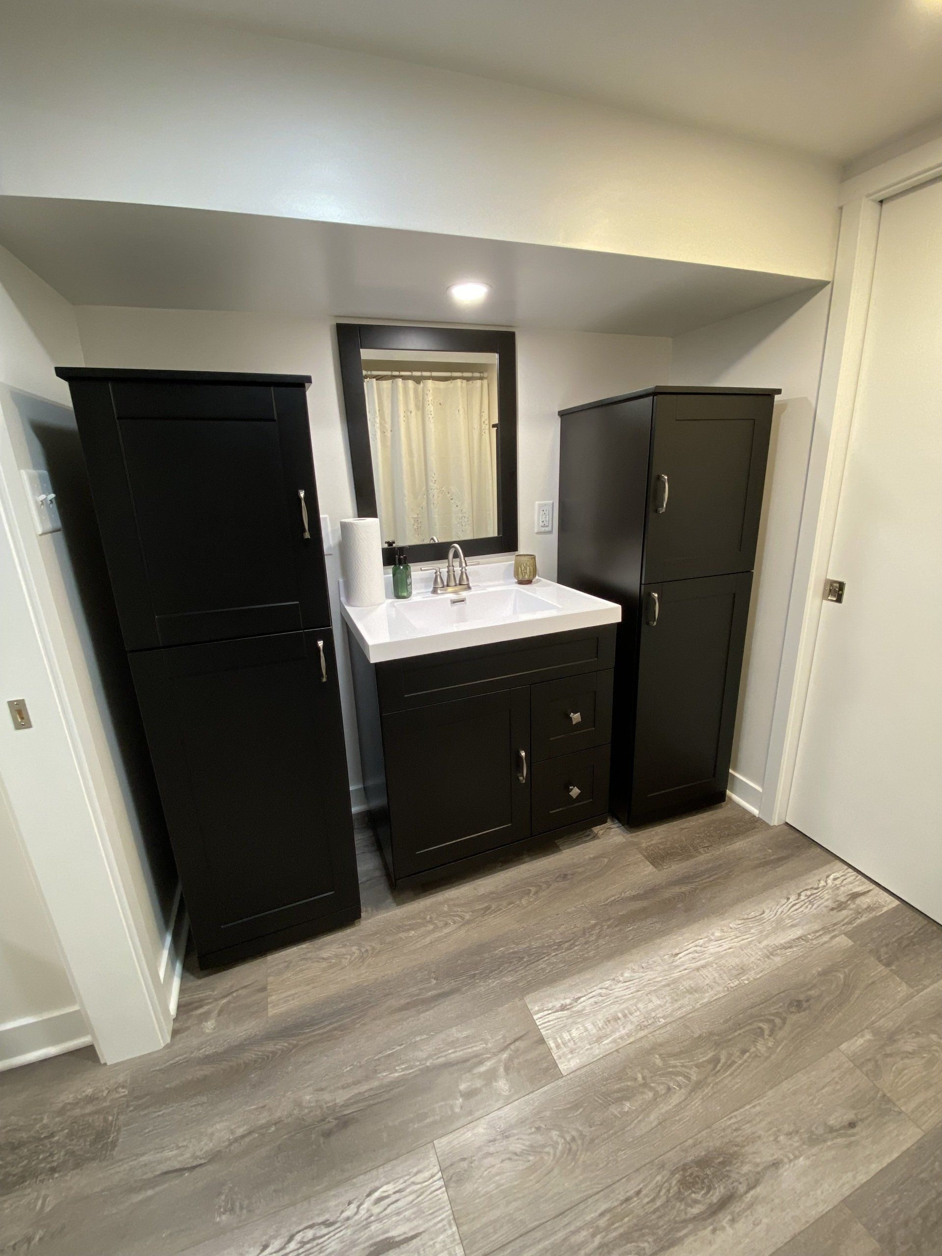 A bathroom with a sink , mirror and cabinets.