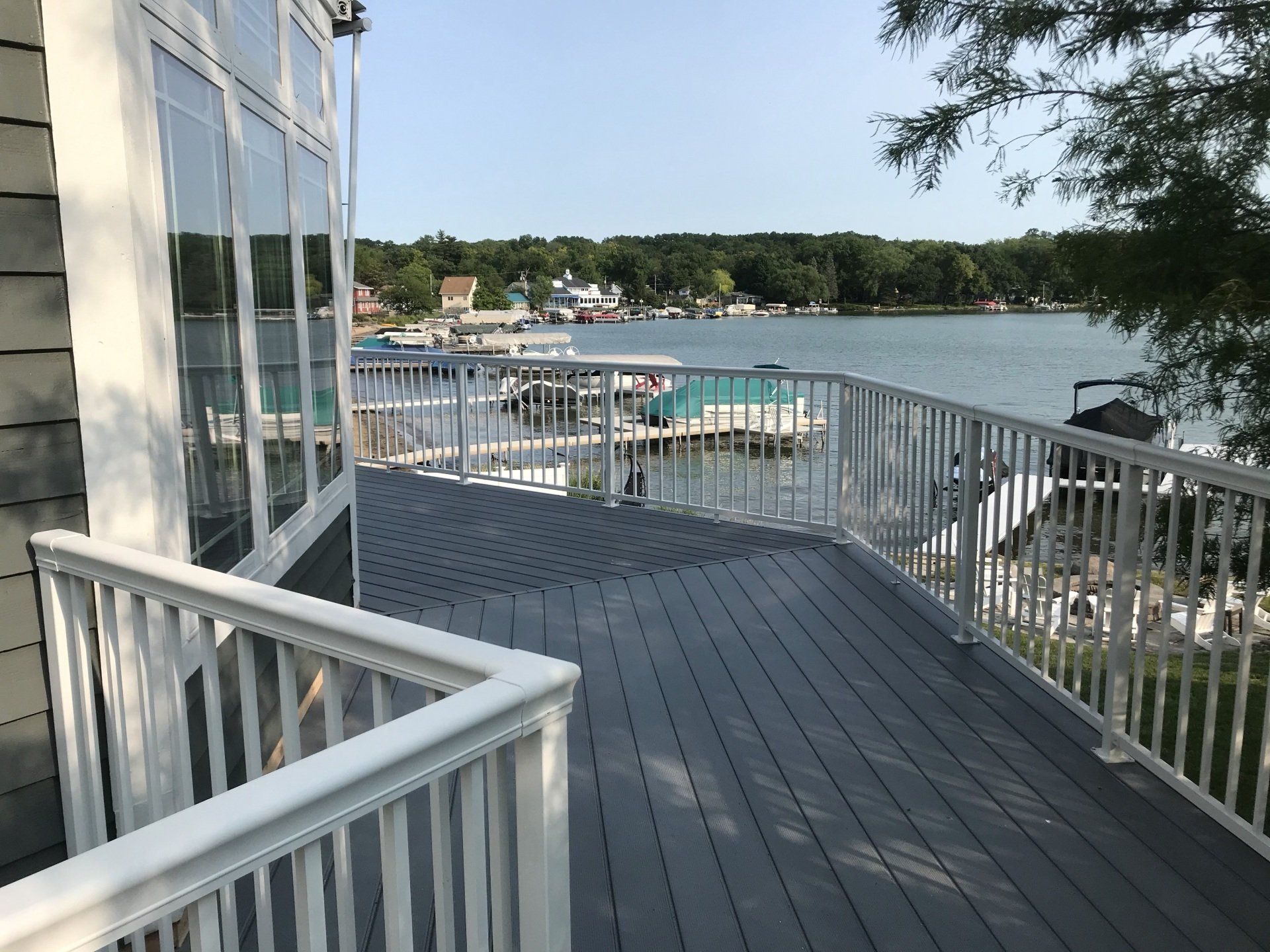 A large deck with a white railing overlooking a lake