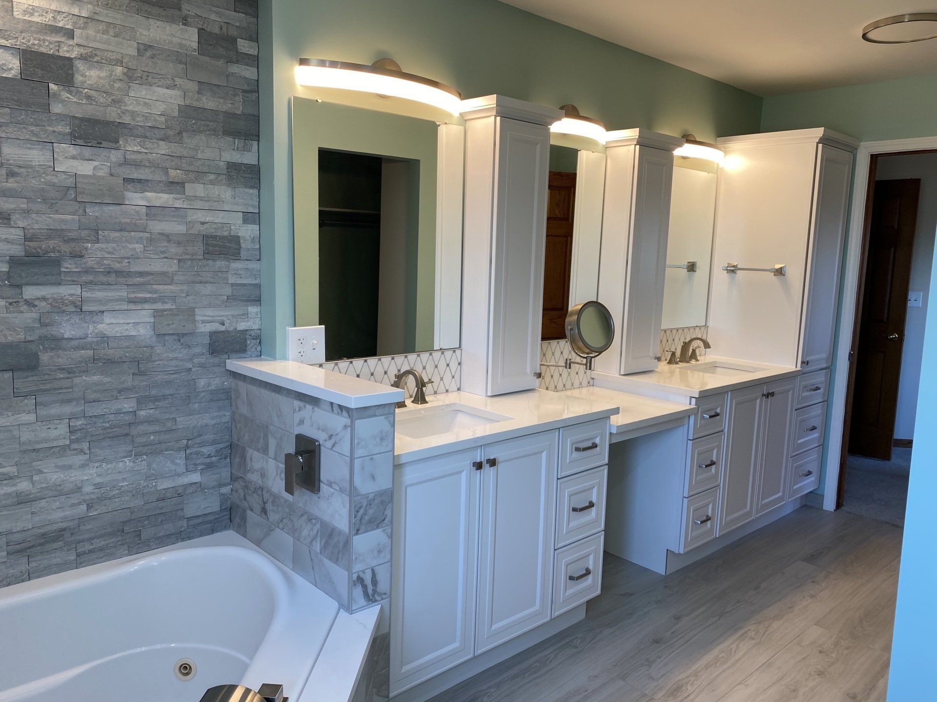 A bathroom with two sinks , two mirrors and a bathtub.