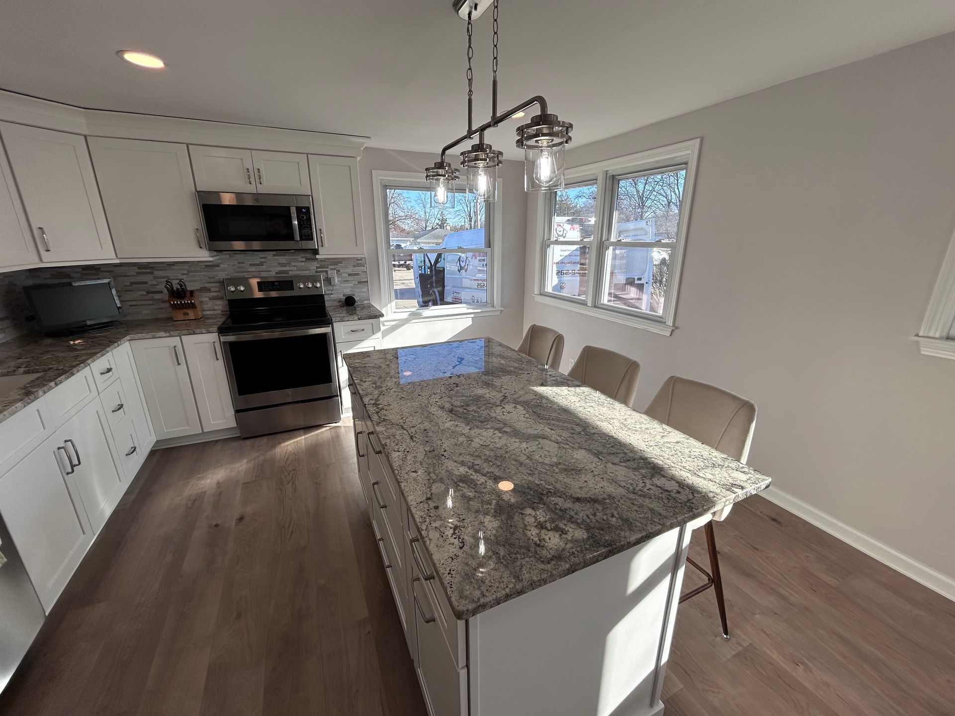 A kitchen with granite counter tops , stainless steel appliances , and white cabinets.