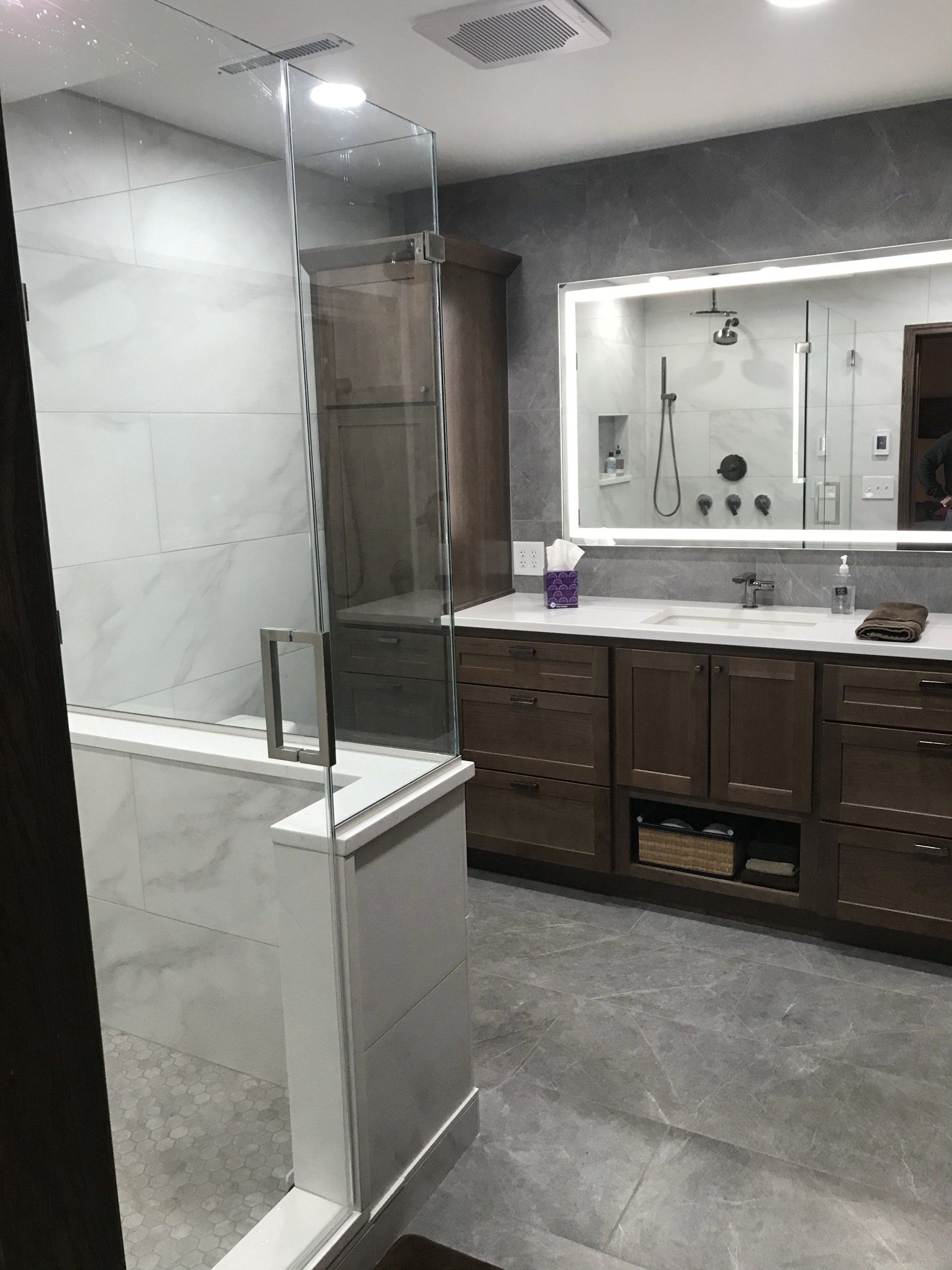 A bathroom with a walk in shower , sink and mirror.