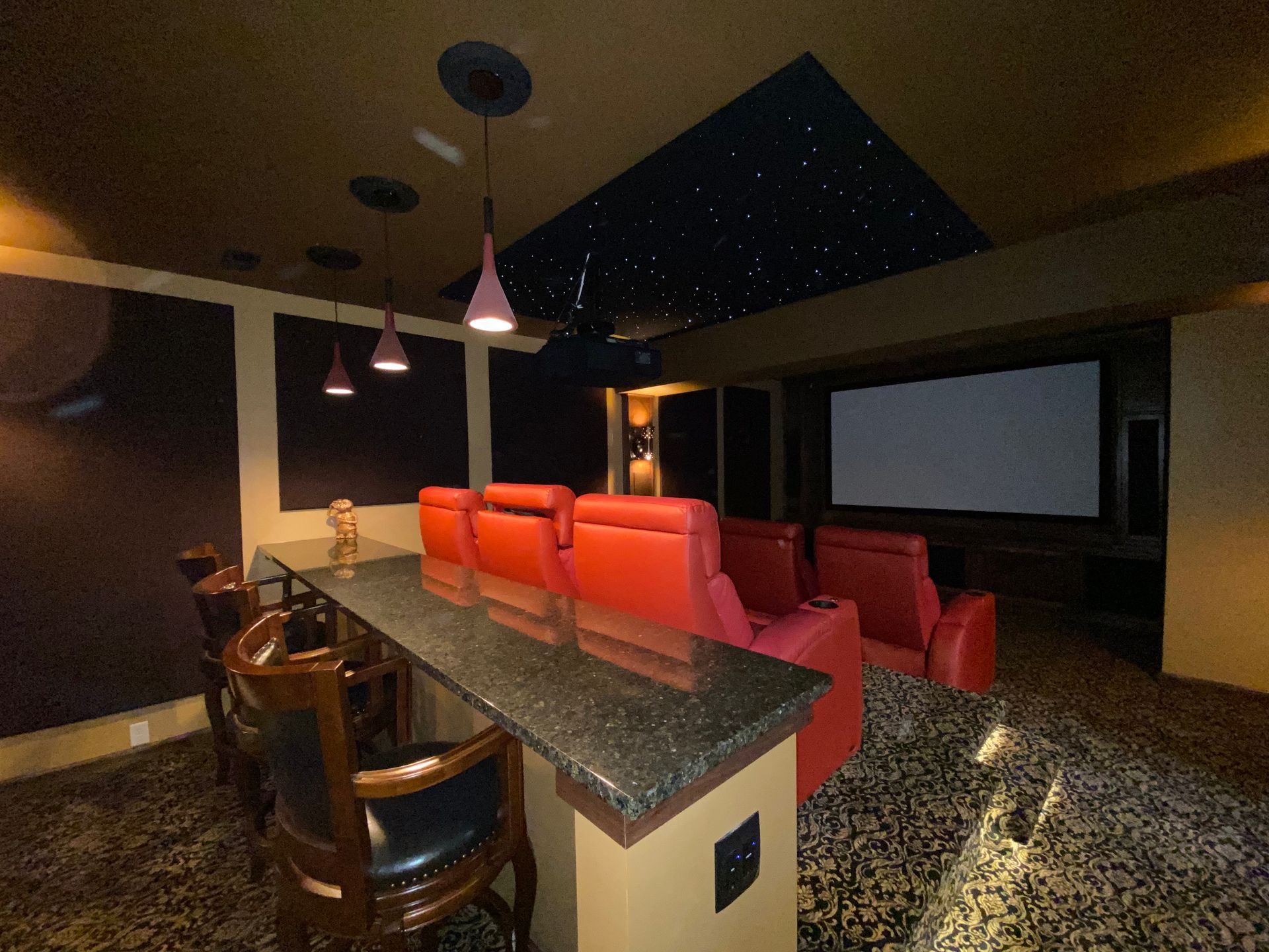 A home theater with red seats and a bar