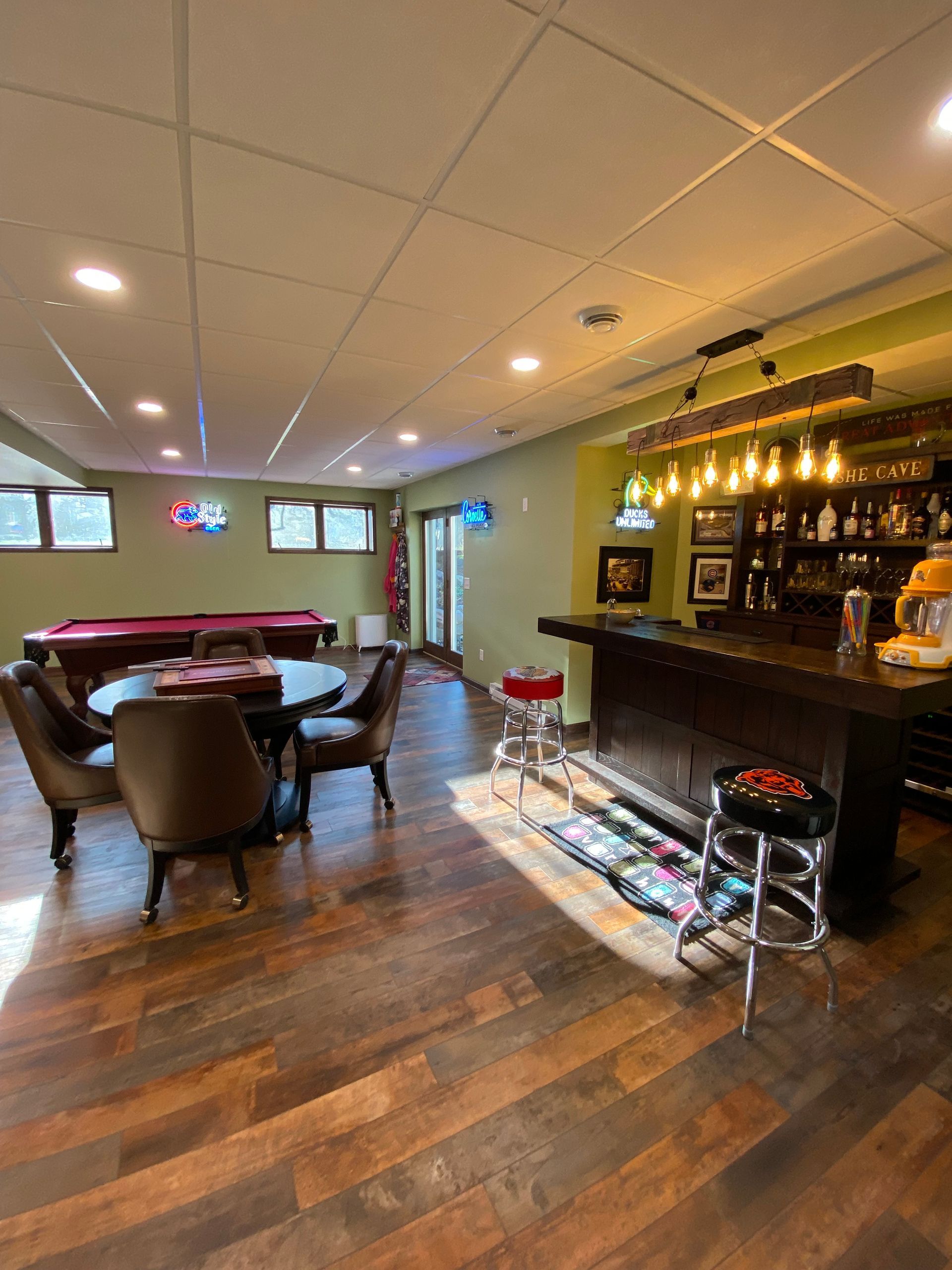 A basement with a pool table and a bar.
