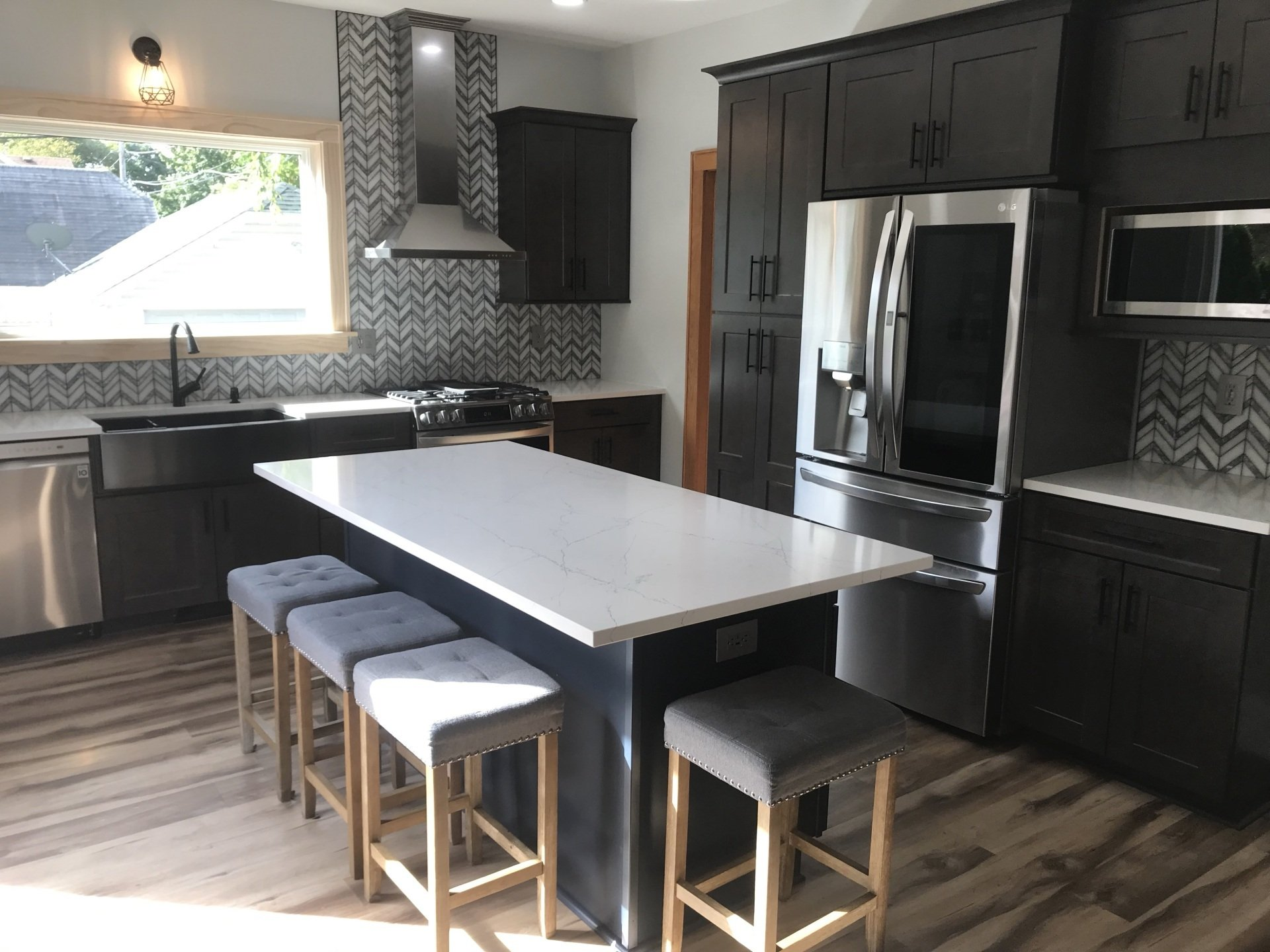 A kitchen with stools and a large island in the middle.
