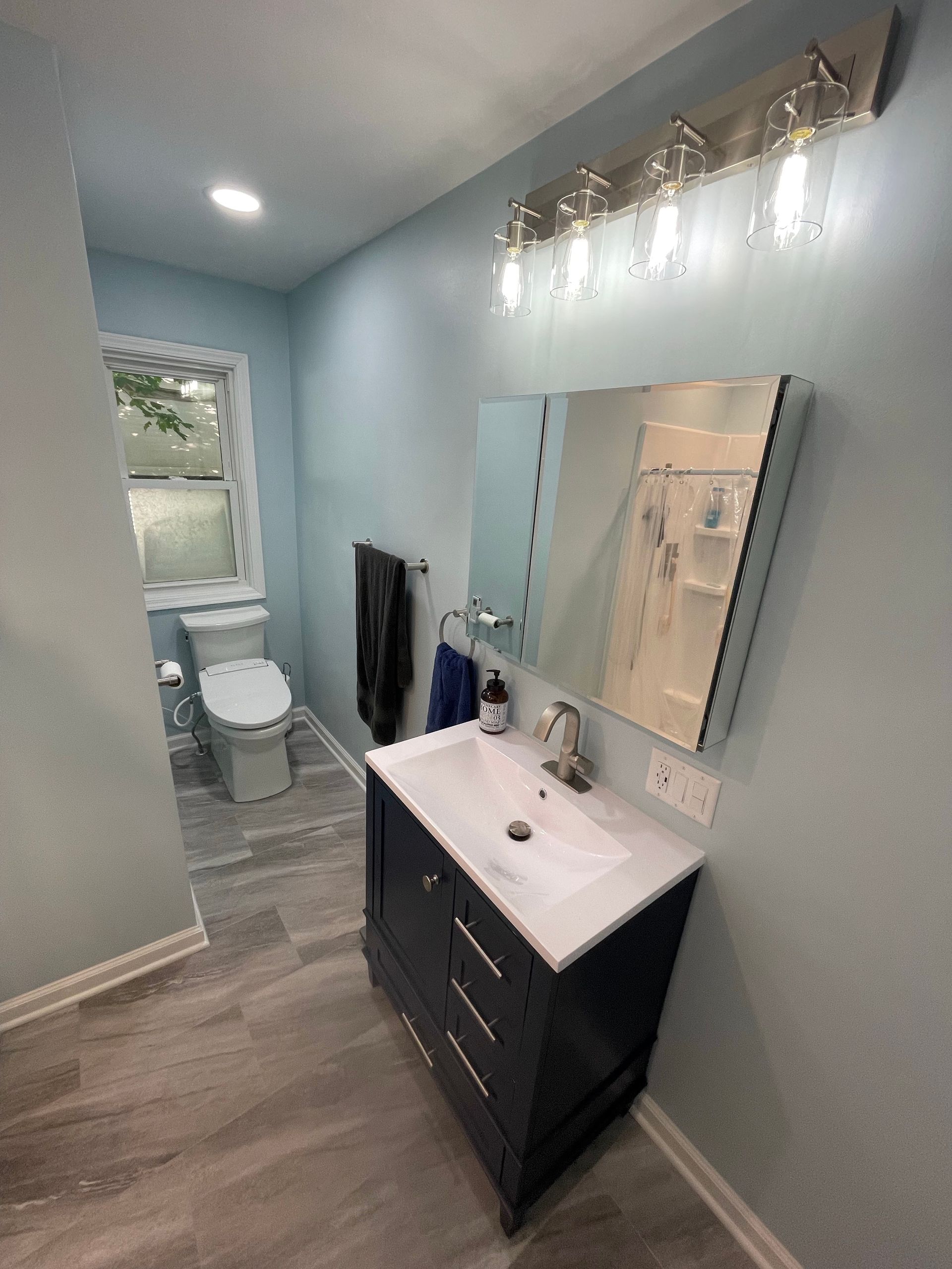 A bathroom with a sink , toilet and mirror.