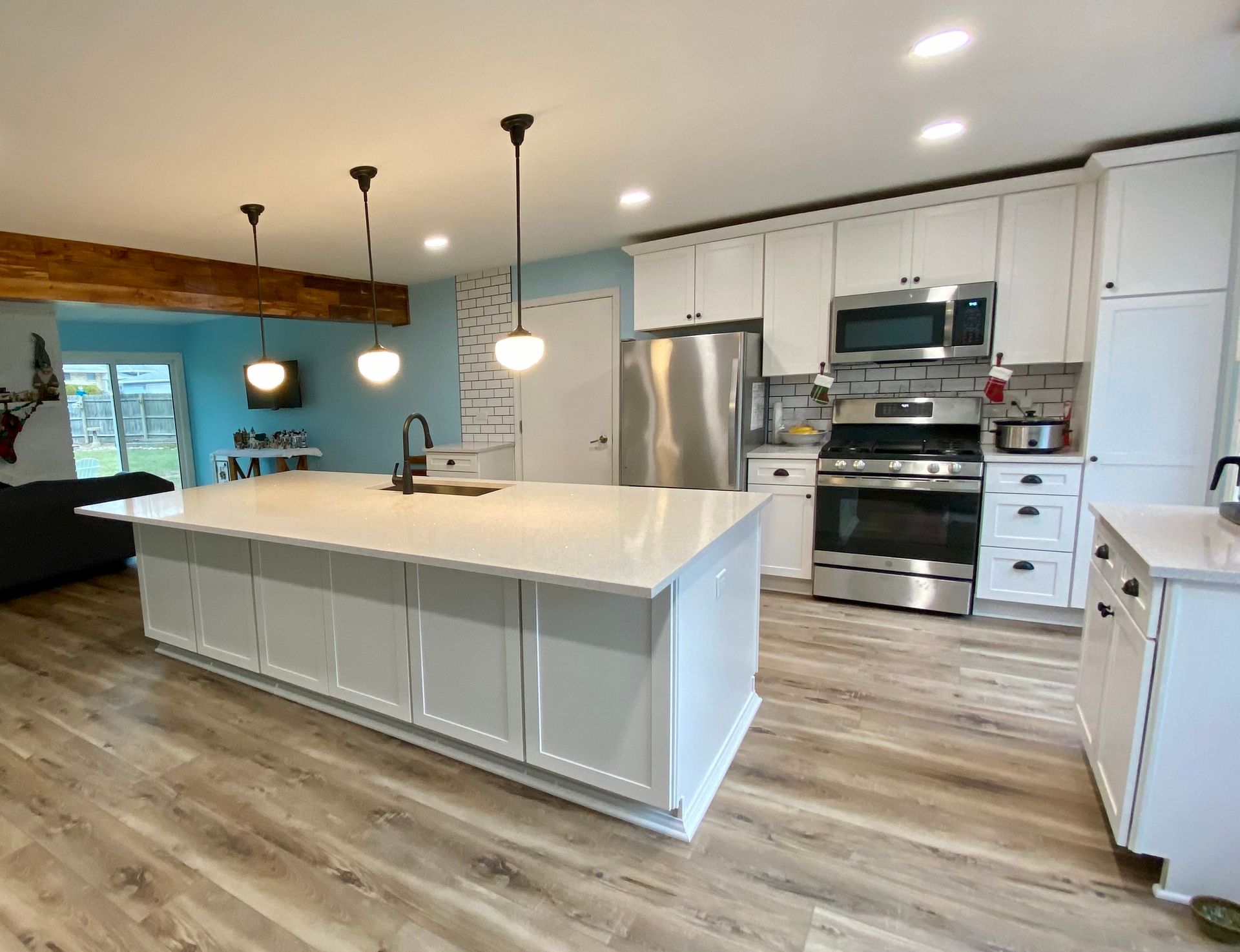A kitchen with white cabinets , stainless steel appliances , and a large island.