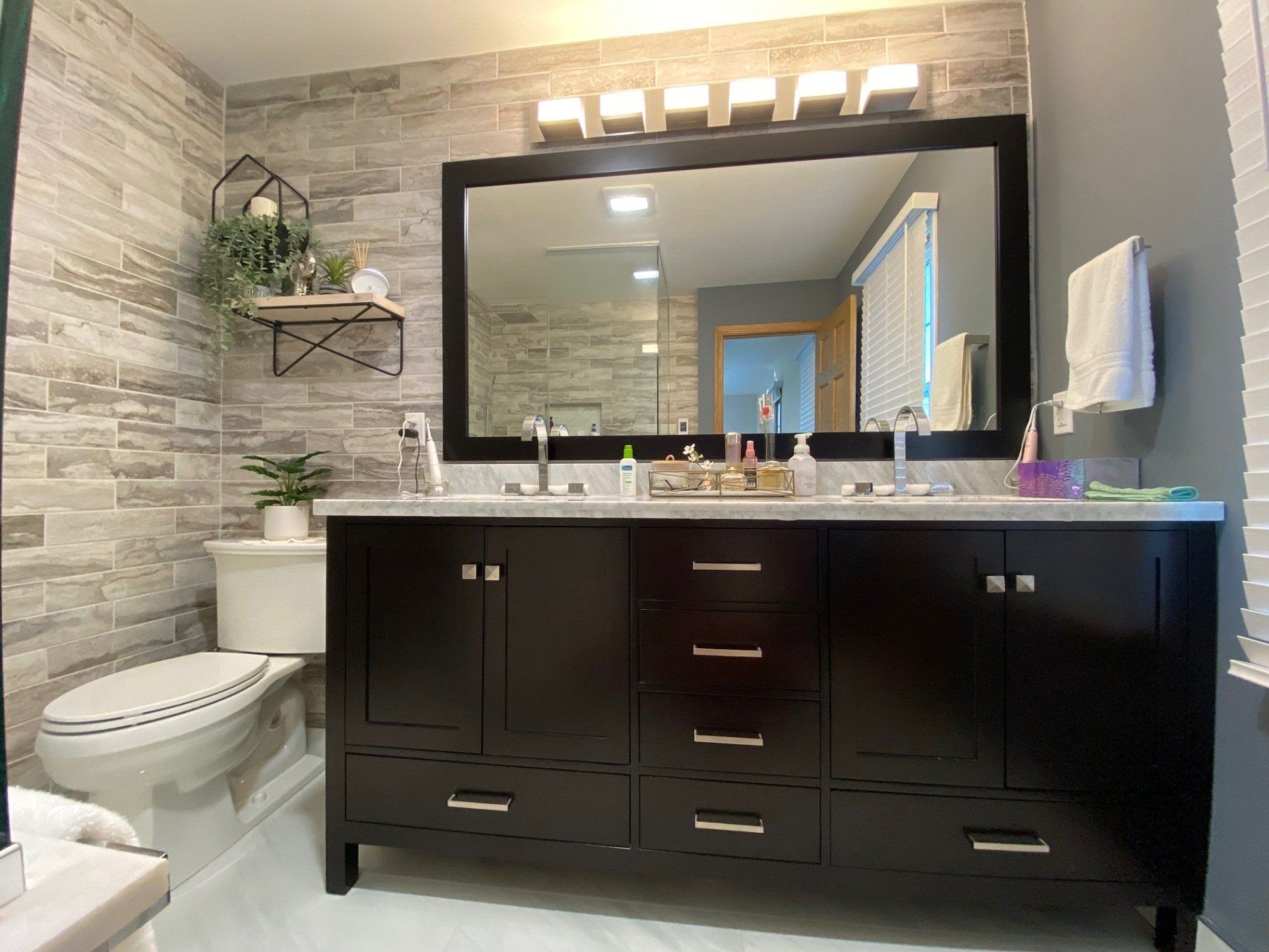 A bathroom with two sinks , a toilet , and a large mirror.