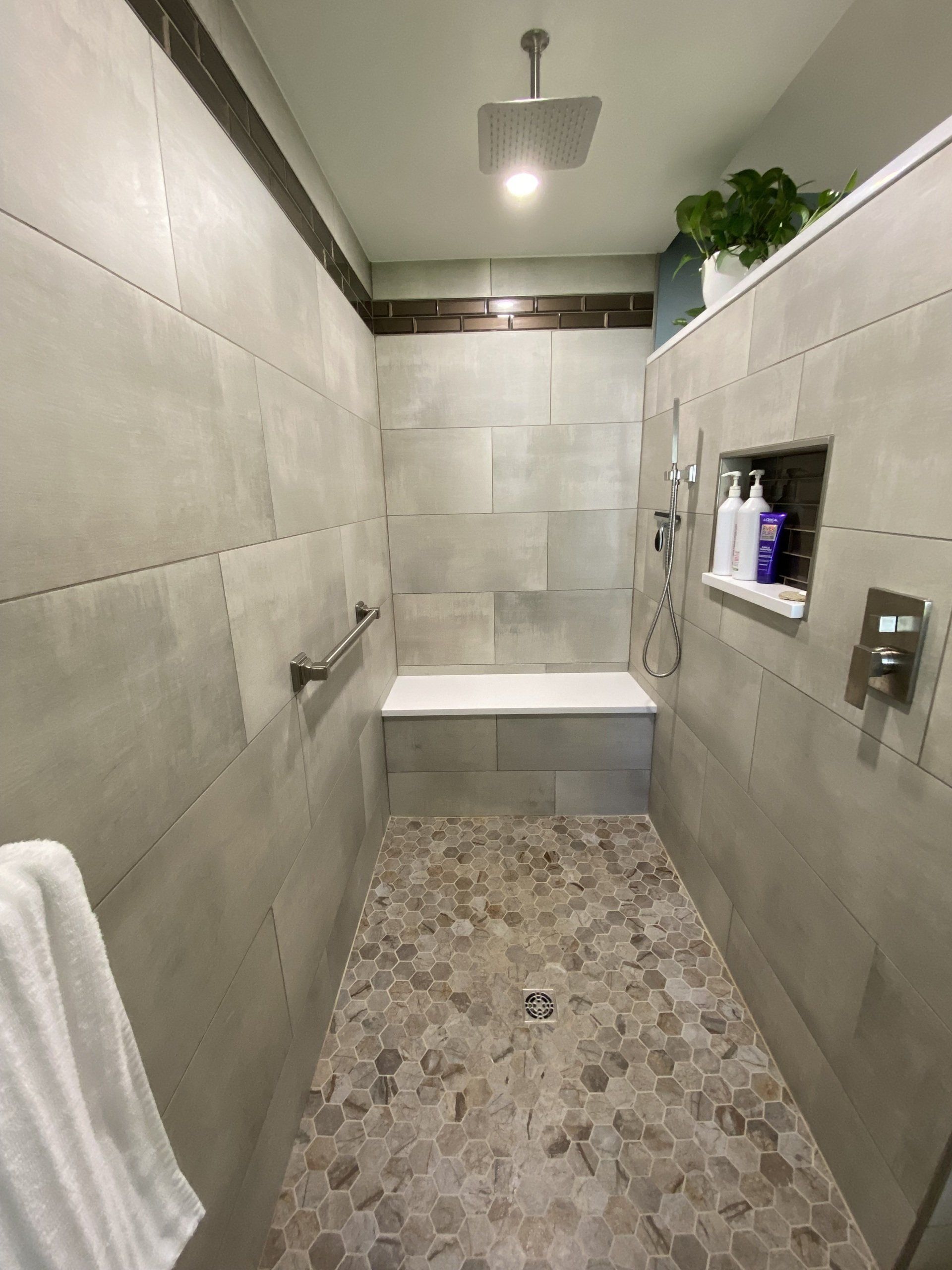 A bathroom with a walk in shower and a bench.