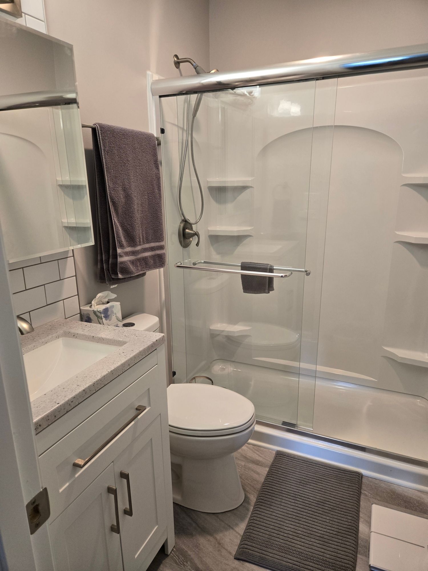 A bathroom with a toilet , sink , shower and mirror.