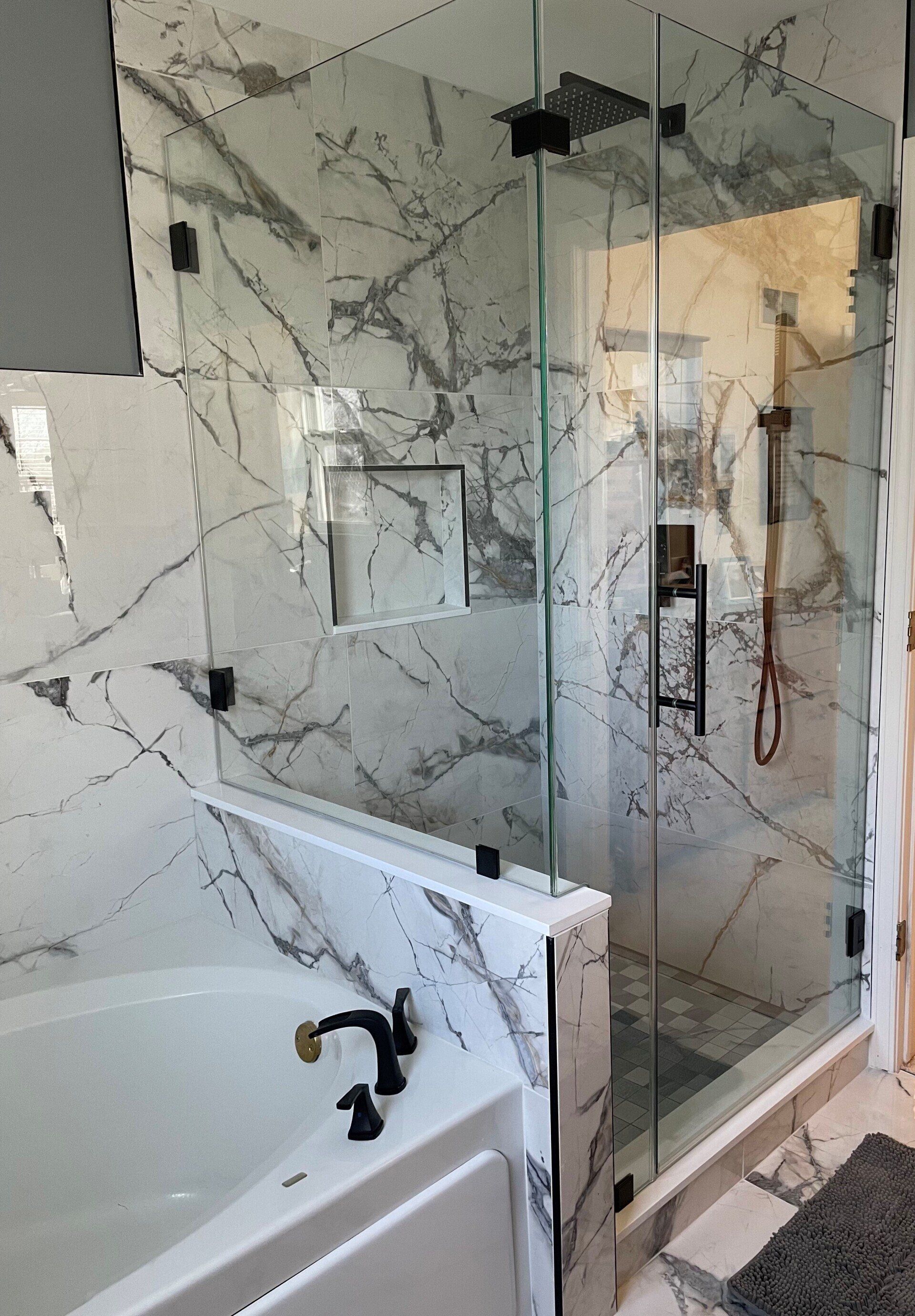 A bathroom with marble walls , a tub , and a walk in shower.