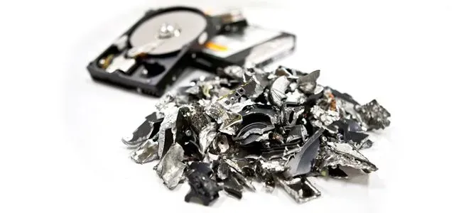 Shredded hard drives with components on a white surface, suggesting data destruction and disposal.