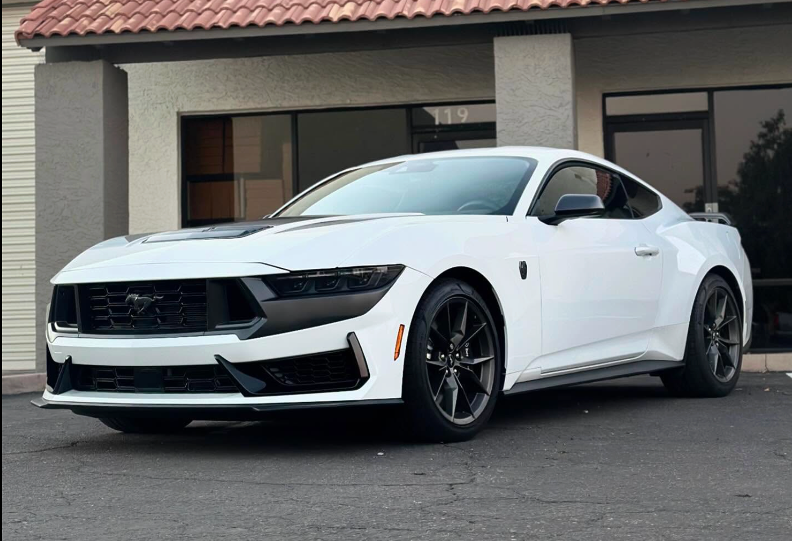White sports coupe parked in front of a building with a tiled roof