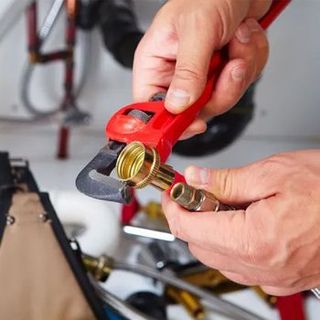 A plumber is fixing a pipe with a wrench.