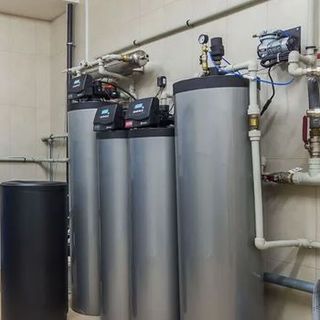 Three water heaters are sitting next to each other in a room.