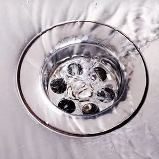 A close up of a sink drain with water running down it.