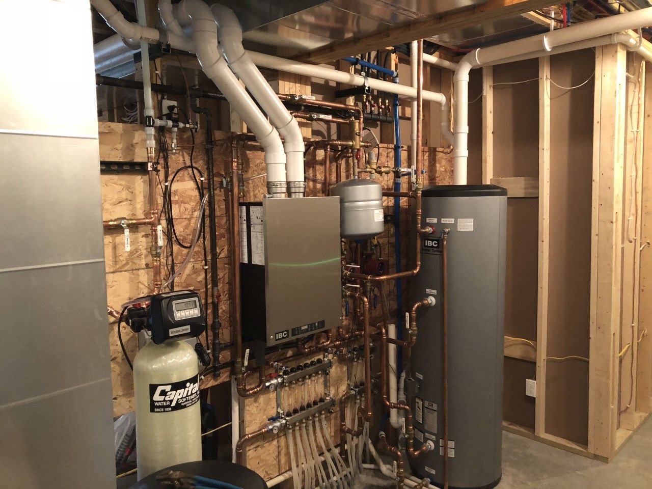 A basement with a lot of pipes and a water heater.