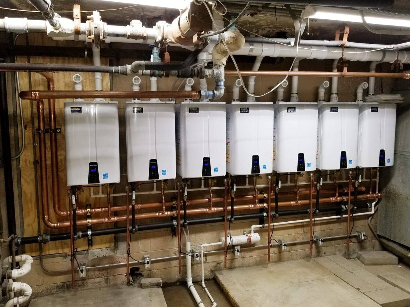 A bunch of water heaters are lined up on a wall