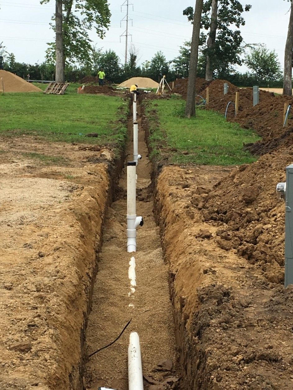 A pipe is being installed in a trench in the dirt.