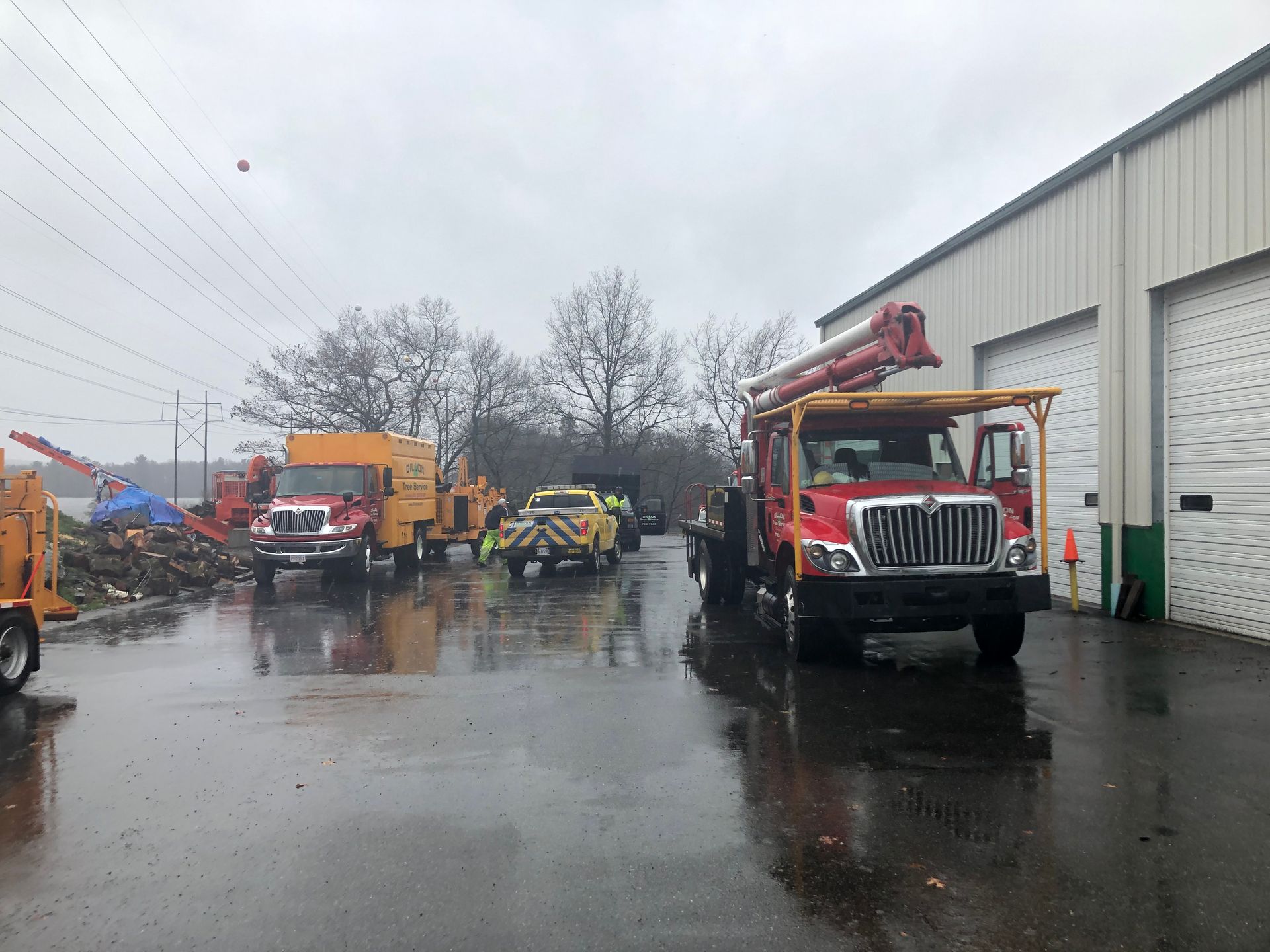Utility trucks parked outside a building on a wet day, ready for work.