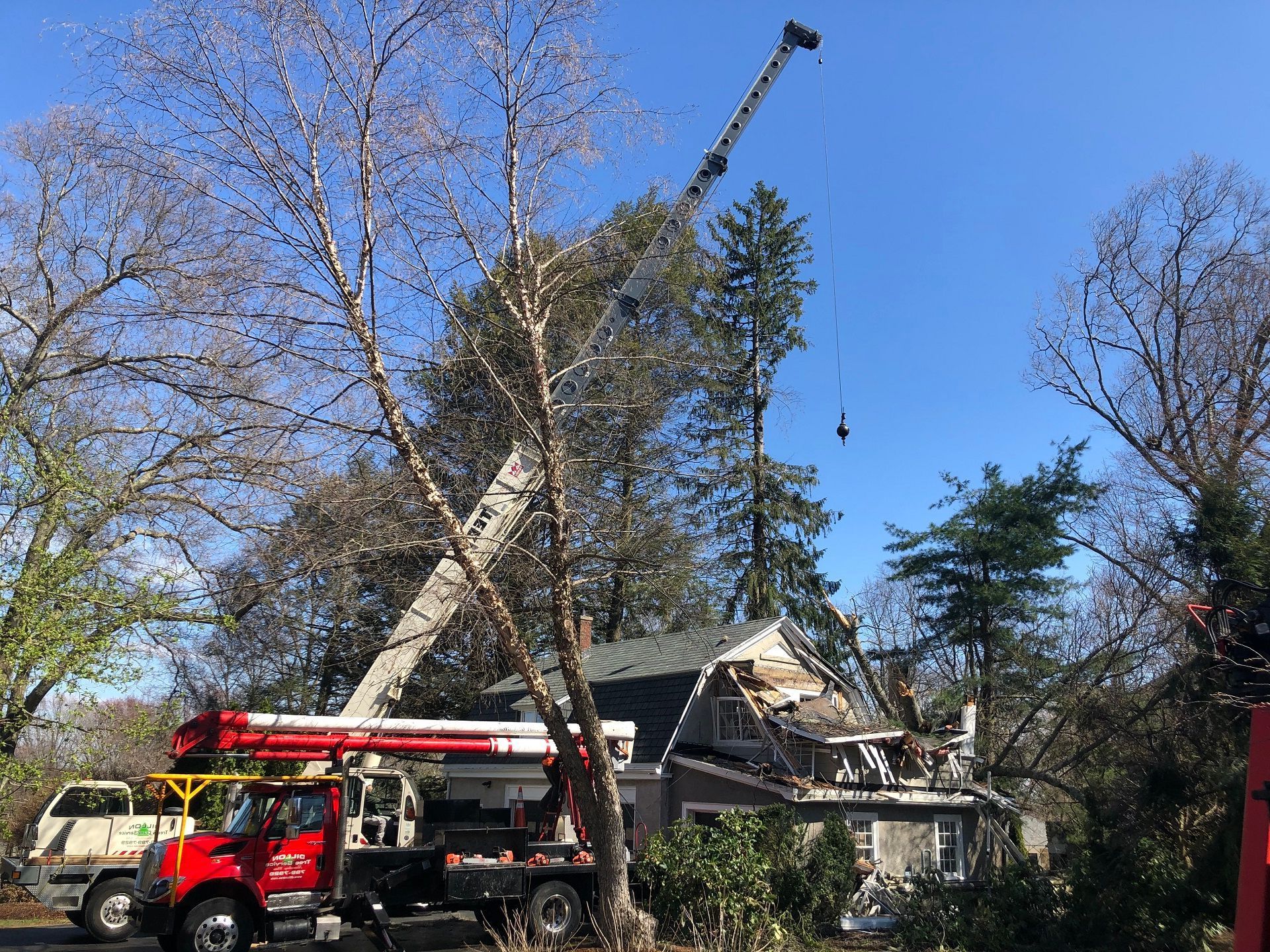 Crane removing roof from house on a sunny day.