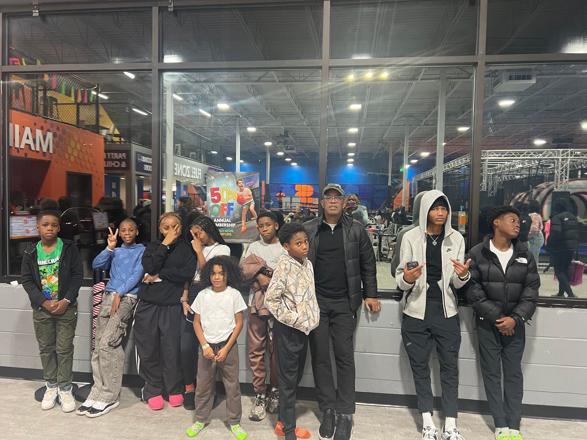 Group of people standing together indoors at a brightly lit storefront, posing for a photo