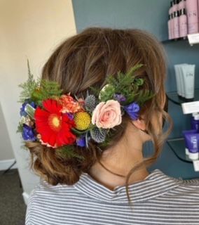 A woman is wearing a bun with flowers in her hair.