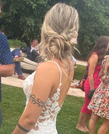 A woman in a wedding dress has a tattoo on her arm