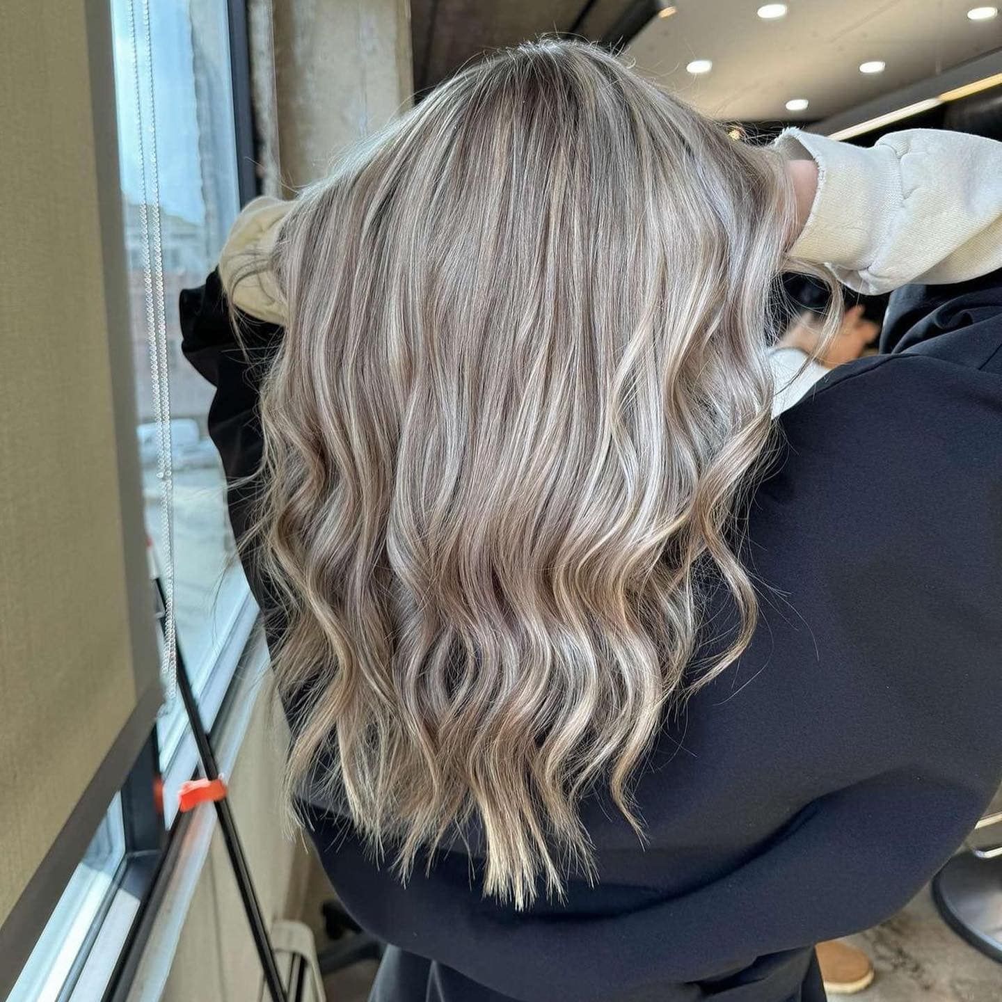 A woman with blonde hair is standing in front of a window.