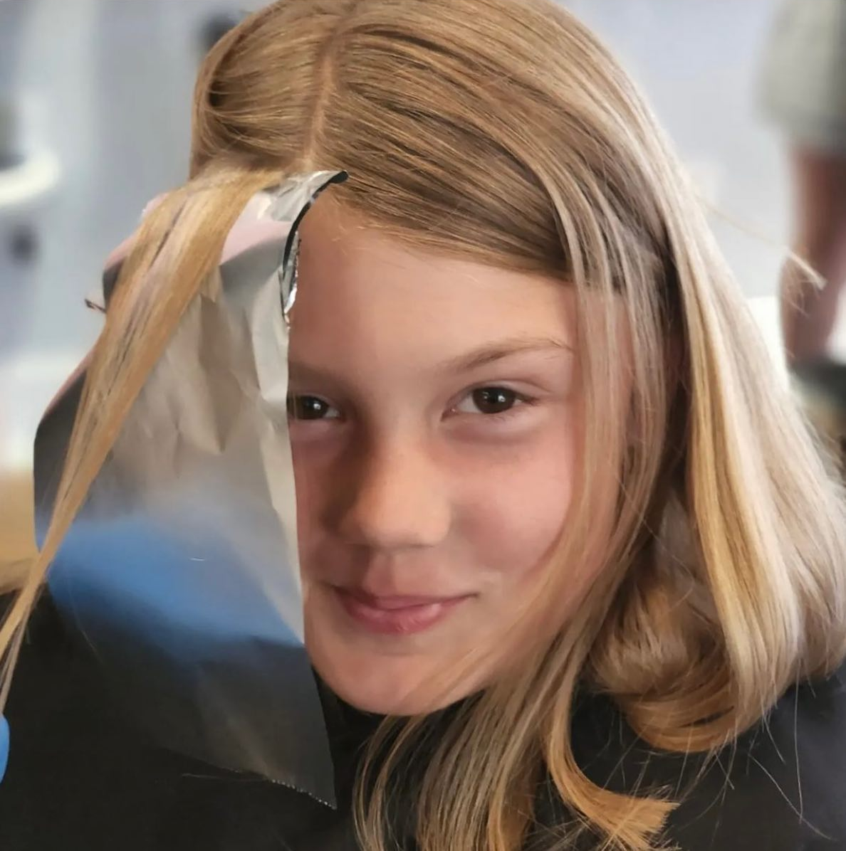 A young girl wearing a face shield looks at the camera