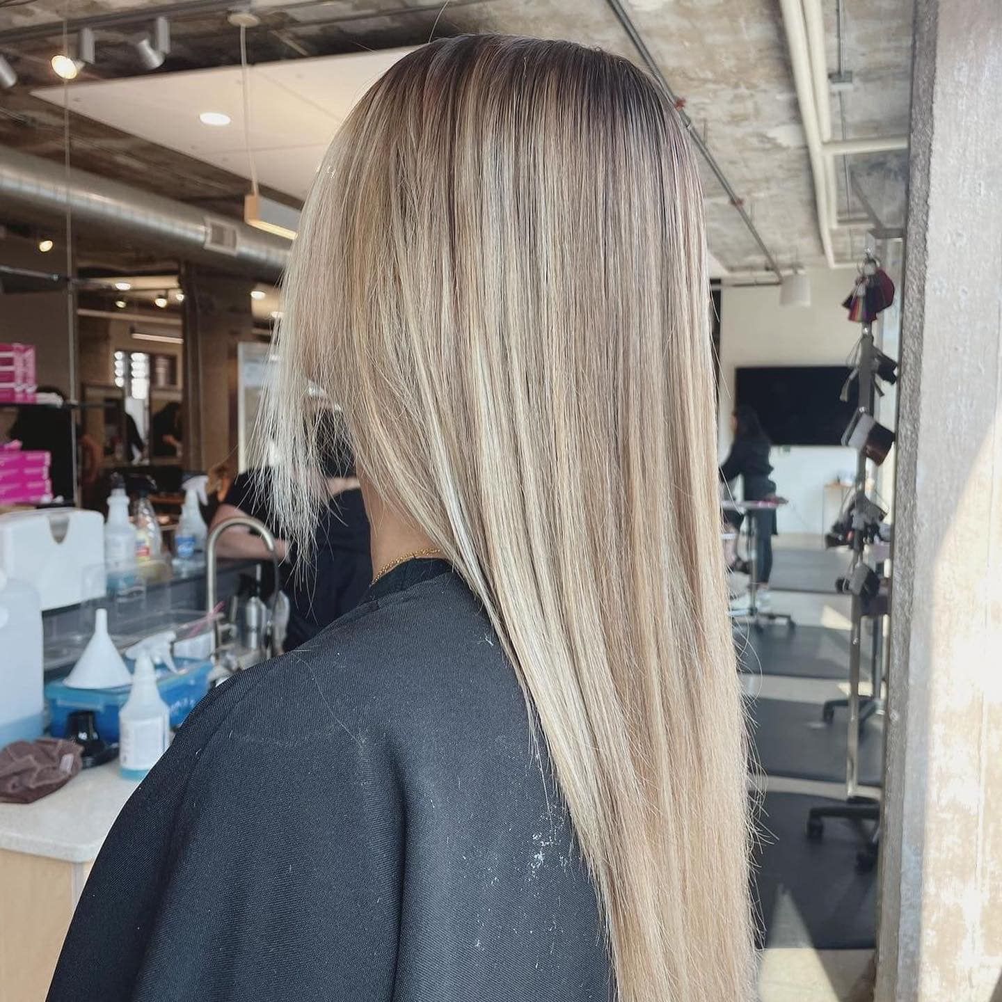 A woman with long blonde hair is wearing a black cape