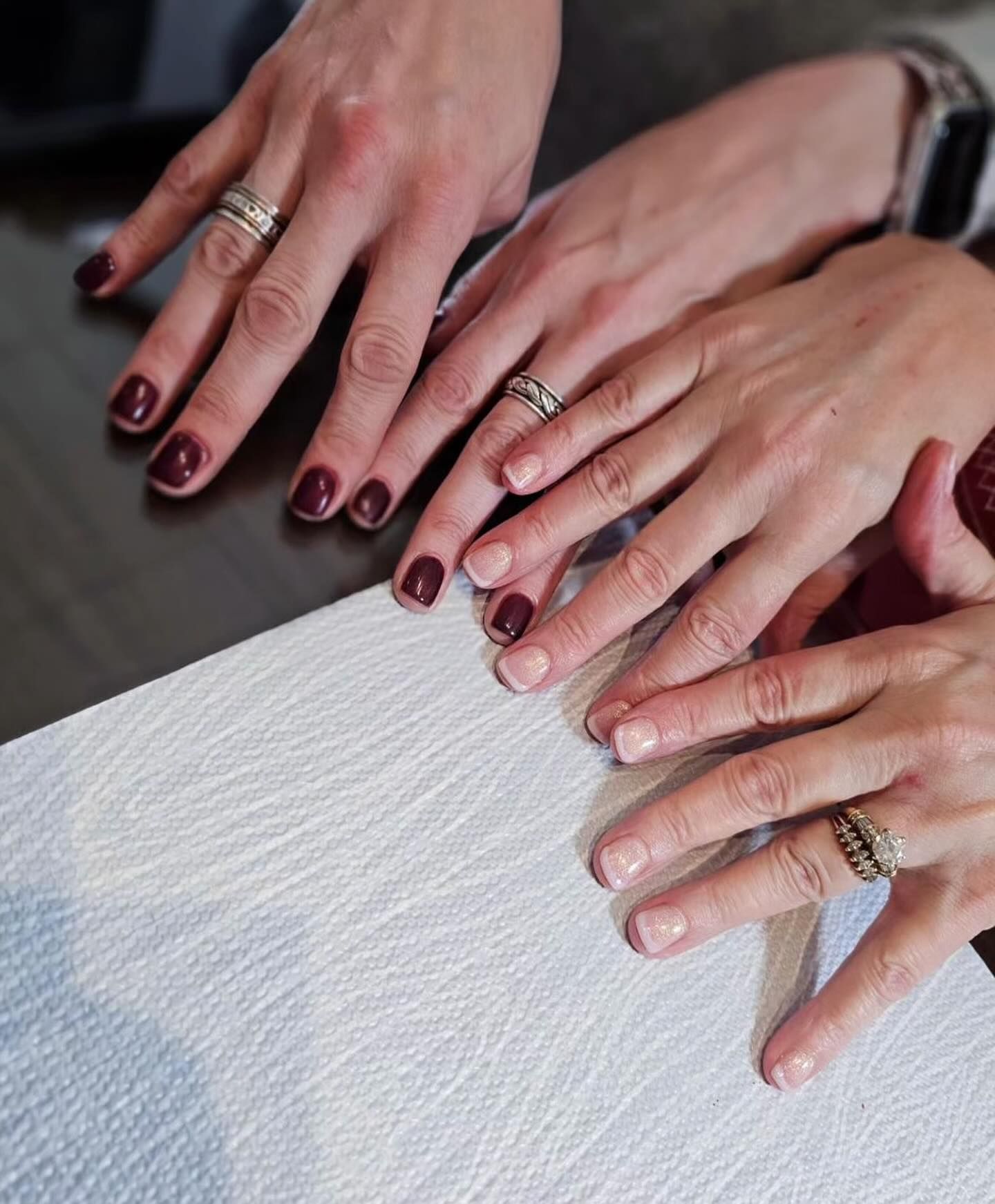 A group of women 's hands are stacked on top of each other on a table.