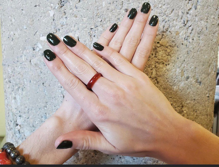 A woman 's hands with black nails and a red ring