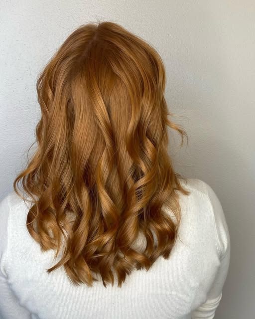 A woman with long red hair is wearing a white shirt.