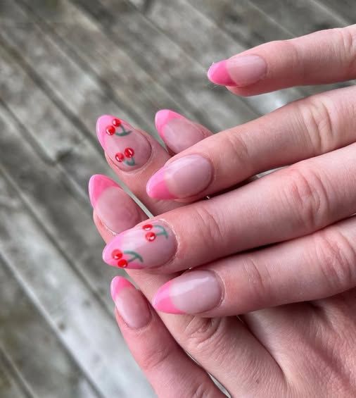 A close up of a woman 's nails with cherry designs on them